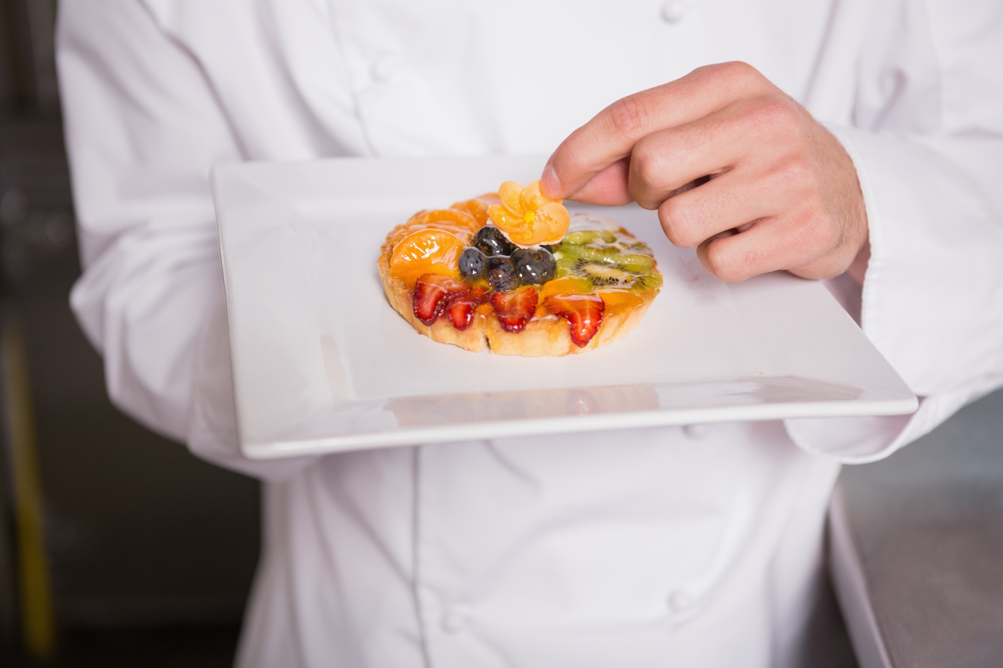chef calibrating modern plating on stainless counter